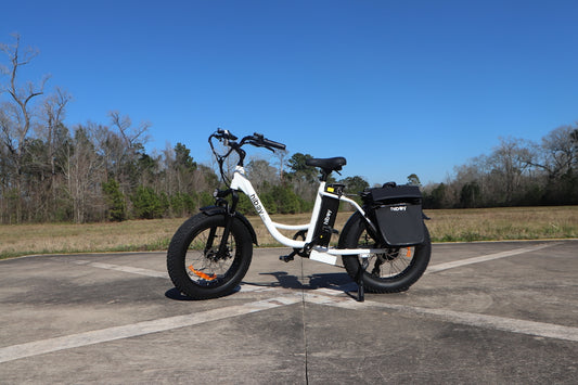 A white electric bicycle stands on pavement.